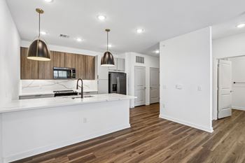 Open concept kitchen with marble countertops and pendant lights